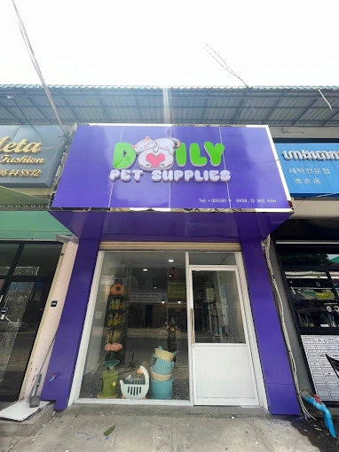 The Daily Pet Supplies storefront in Sen Sok, Phnom Penh: a bright purple shopfront with the sleeping calico cat logo on the signboard, above glass doors looking through to the shelves inside
